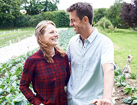 rural couple hugging with greenery behind them 